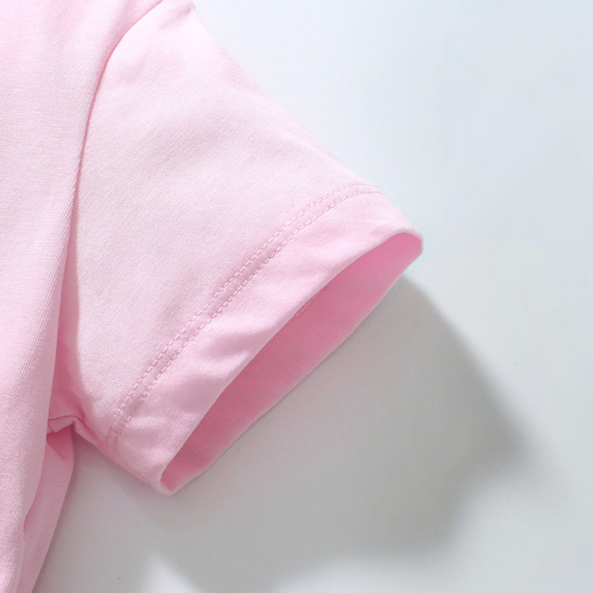 Close-up of the soft pink cotton-blend short sleeve on a BabyEase girls' bunny appliqué tulle dress.